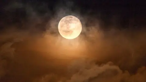 Atmospheric Moon peaking out amongst clouds