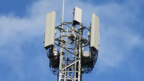 Getty Images A mobile phone mast with various dishes and antenna against a blue sky