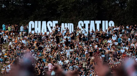 Sam Neill Chase & Status logo in the crowd