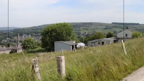 A photograph of the farm where the houses could be built surrounded by wooden fences and wire