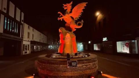 Somerset West and Taunton Council a dragon sculpture on a high street illuminated orange