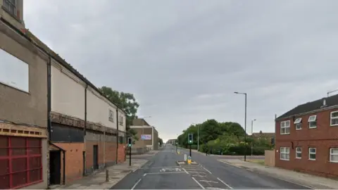 The junction of Oxford Street and Victor Street in Grimsby. It has a set of traffic lights and buildings on both side of the road.