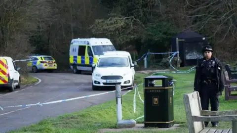 PA Media A number of police vehicles are at the scene of the incident, with a cordon in place and a police officer standing just outside the cordon. A number of benches can also be seen and a dark blue forensics tent is in place