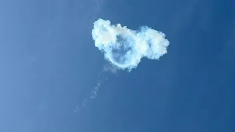 Faye Morton A blue sky with white smoke in a circular shape, which is a photo of a missile being intercepted in the sky above Doha. 