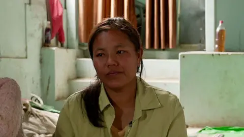 BBC Iang Za Kim, sitting in a green shirt on the floor of a community centre in India