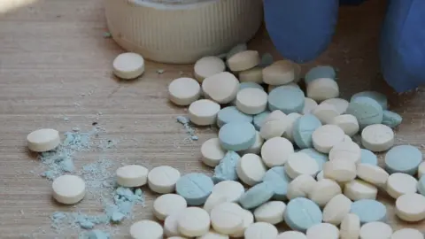 AP A police officer counts pills during a drugs raid, September 2010