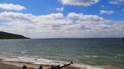 Sunny skies with a few clouds over Totland beach