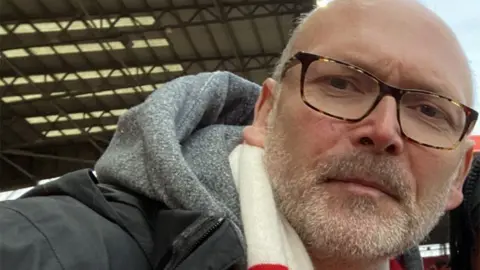 A close  up image of Andrew Davies who has a beard and a Middlesbrough scarf on