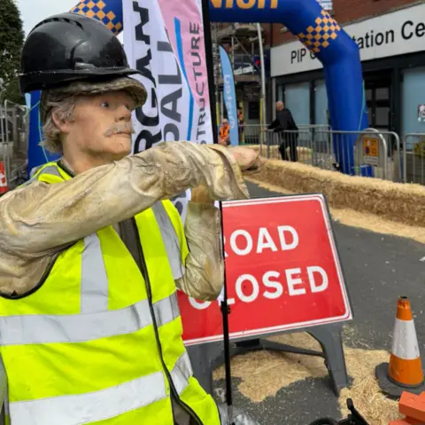Barrow BID A mannequin wearing construction workers clothing stands in front of a 'road closed' sign, as part of the racing track at Barrow soapbox derby.