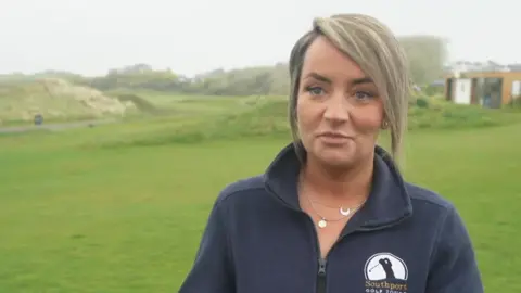 Victoria Palmer, who is wearing a navy fleece with Southport Golf Tours logo, is standing on the middle of a golf course during an interview with BBC North West Tonight. 