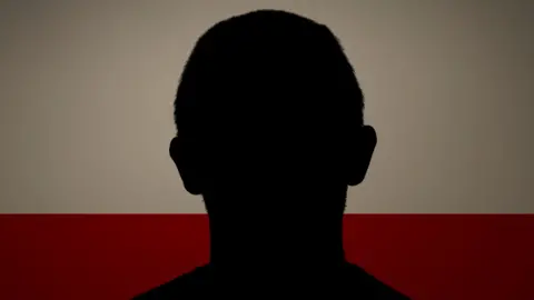 A silhouette of a man having his picture taken for a mugshot