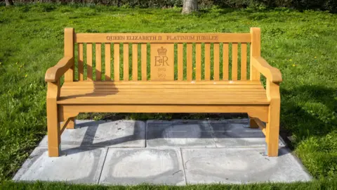 Getty A golden bench in a park which says Queen Elizabeth II Platinum Jubilee. It also has the late Queen's emblem. 