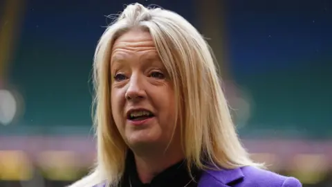 David Davies/PA Wire A head and shoulders picture of Abi Tierney smiling and looking to the side of the camera. She is wearing a light purple jacket over a dark top. Stands in the Principality Stadium can be seen blurred in the background.