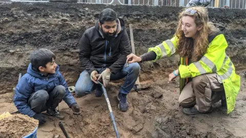 Rochdale Borough Council L-R Zakariya with his father Azhar Sacranie and archaeologist Ashley Brogan