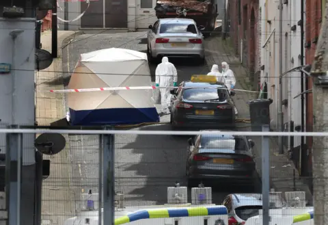 Margaret McLaughlin, forensic scientists in white suits on Harvey Street, white tent on the street in front of a property, police cordon and a vehicle blocking the street