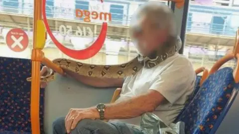 PA Media Man using snake as face mask