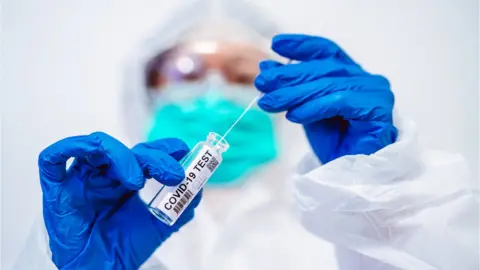 Getty Images/Tang Ming Tung Health worker holding Covid-19 test sampling swab