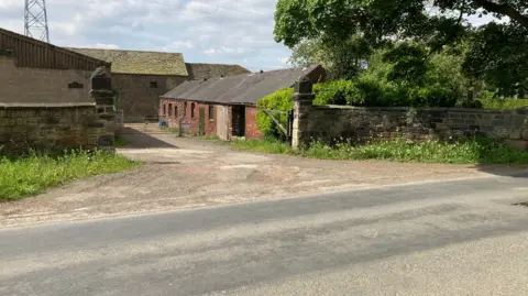 LDRS Farm buildings and a barn off a main road.