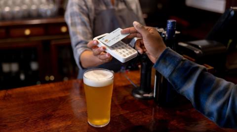 Close-up on a man making a contactless payment at the pub