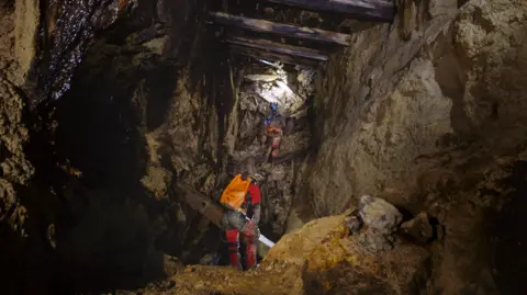 Tim Clarke Two men explore an old Cornish mine working, both are wearing safety equipment 