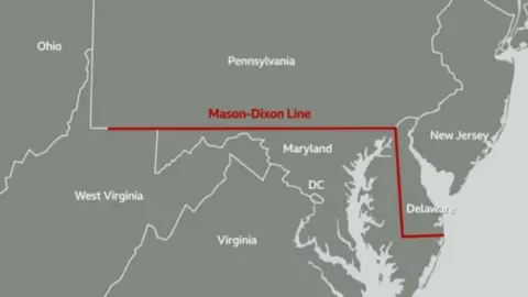 A map showing part of eastern US, encompassing the states (clockwise) Ohio, Pennsylvania, New Jersey, Delaware, Maryland, DC, Virginia, West Virginia. The Mason Dixon line, which is shown in red, runs east to west through southern Pennsylvania, north to south through Delaware and east to west through Delaware to the eastern coast.