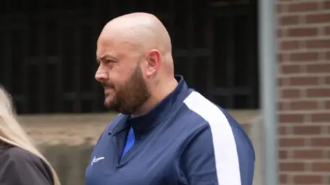 Dominique Saunders pictured leaving Merthyr Crown court. He wears a navy hooded jacket with white stripes on the shoulders. Paul Lewis was alleged to have paid Dominique Saunders to arrange the murder of his wife Joanne Atkinson. Both men denied the charges.