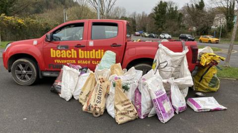 Beach Buddies' red truck with bags of rubbish