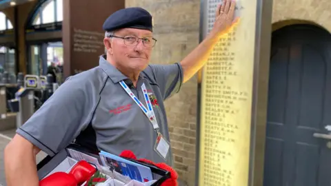 Denis Scaife touching the King's Cross station war memorial in London