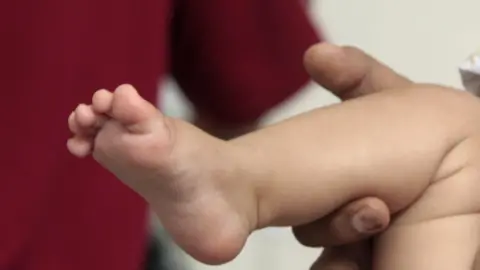 Getty Images An adult holds a baby's foot