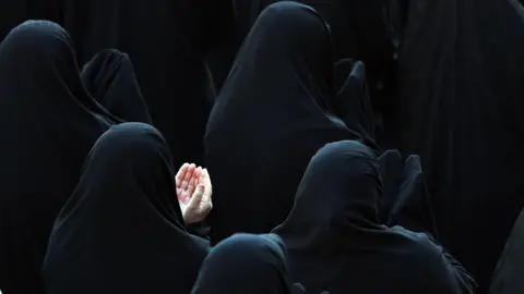 EPA/Shutterstock Women, wearing hijabs, with their backs to the camera are praying for rain in northern Tehran.