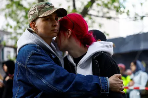 Valentyn Ogirenko / Reuters A close up image shows two residents embracing while standing outside the site of the attack on Thursday.