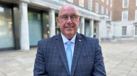 Nottinghamshire County Council leader Mick Barton is pictured wearing a blue-striped blazer, shite shirt and powder blue tie