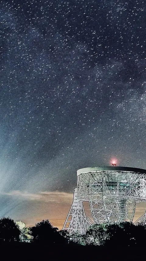 The Lovell telescope shining on a dark clear night at Jodrell Bank 