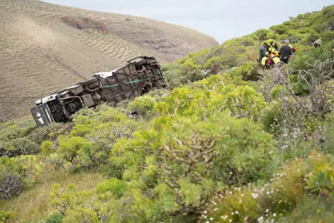 Europa Press Canarias via Getty Images A close up of the bus on its side and rescue workers next to it