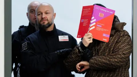 Getty Images A defendant covers his face as he is led into court accused of the Dresden theft