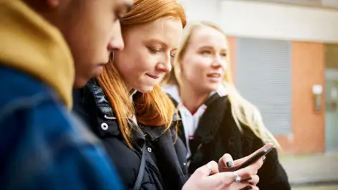 A group of teenagers using a mobile phone