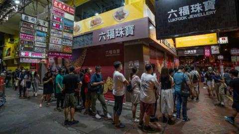 Getty Images Supporters wait in line to purchase the final edition of the Apple Daily newspaper