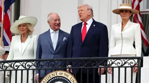 The Queen, King, Donald and Melania Trump stand on the White House balcony in formal attire on Tuesday.