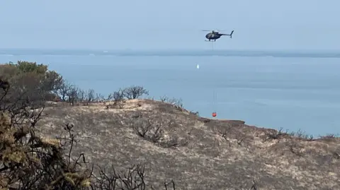 Helicopter over an area of burnt heath on the Isle of Wight coast