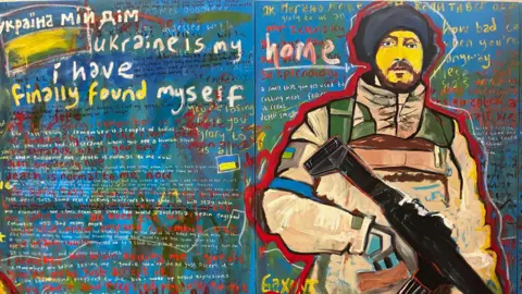 A painting of a Ukrainian soldier carrying a large gun. The background is composed of mostly blue with red, yellow and green, and features messages in Ukrainian and English regarding the war in Ukraine.