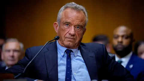 Getty Images US Health Secretary Robert F Kennedy seated in front of a microphone in the US Senate, wearing a blue suit.