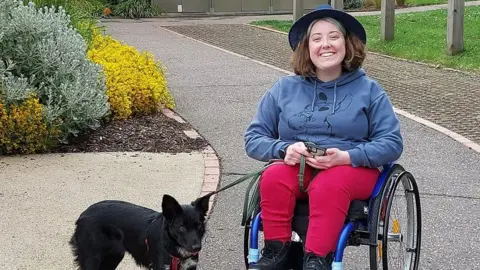 Lucy King Lucy King in her wheelchair with a black dog on a lead next to her