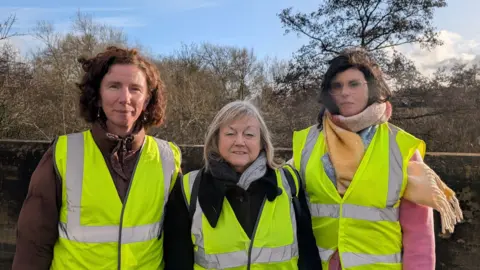 MPs Anneliese Dodds (left) and Layla Moran (right) are pictured with councillor Judy roberts. The trio are standing outside and are wearing yellow hi-vis jackets.