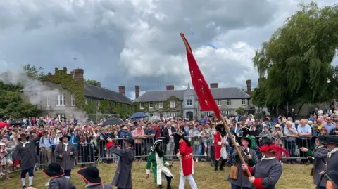 The actor playing King James is on his knees as he is defeated by King William in the battle re-enactment