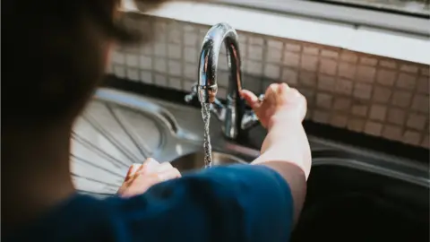 Getty Images Man turns tap - stock shot