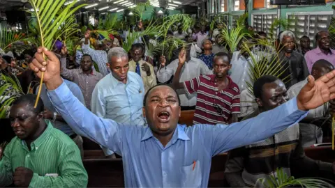 Getty Images Believers pray without taking social distancing during a Palm Sunday mass at the Full Gospel Bible Fellowship Church in Dar es Salaam, Tanzania, on April 5, 2020.