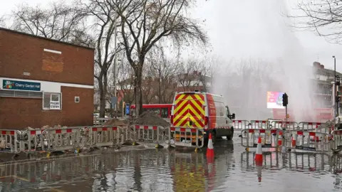 PA Media Water sprays up as the road floods