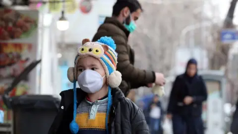 EPA A child wearing a face mask walks on a street in Tehran on 26 February 2020