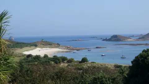 Some small islands scattered in blue sea with a beach and some boats
