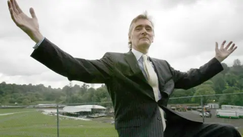 PA Media Lord Henry Mount Charles at Slane Castle in 2004, wearing a dark suit with pin stripes, a shirt with a white collar and a yellow tie.